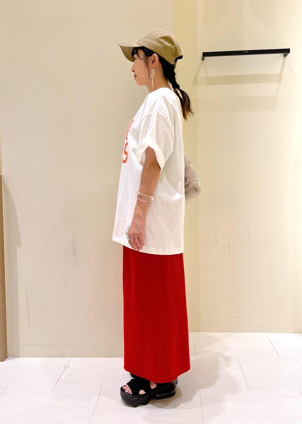 オレンジ系のスカート、ベージュ系のショルダーバッグ、ホワイト系のTシャツ/カットソーを着用したレディースの夏コーディネートの2枚目の写真