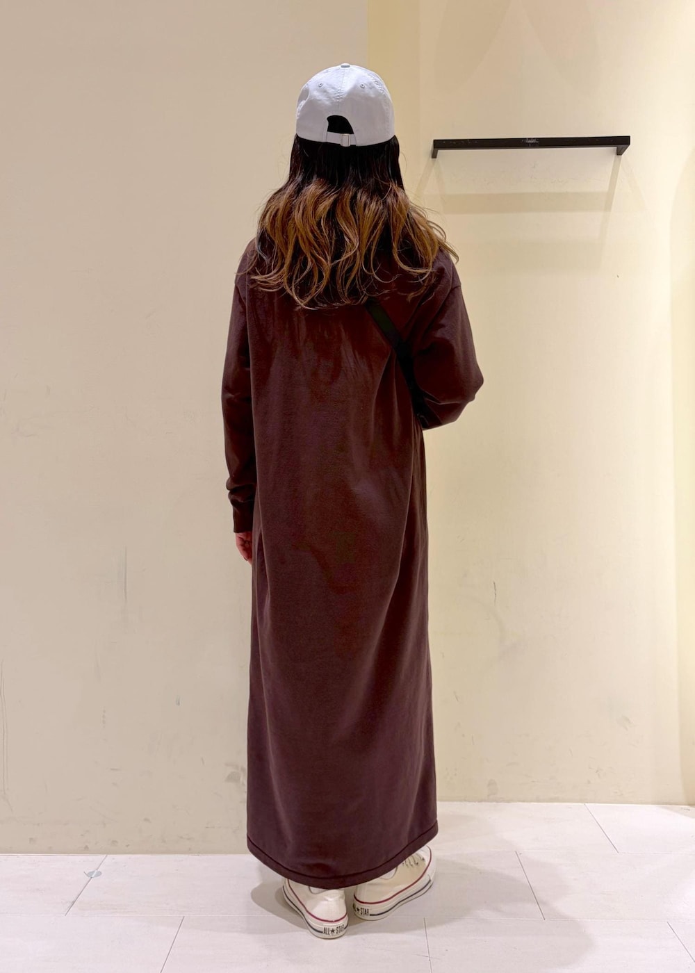 ブラウン系のワンピース、ブラック系のボディバッグ/ウエストポーチ、ホワイト系のスニーカーを着用したレディースの冬コーディネートの3枚目の写真