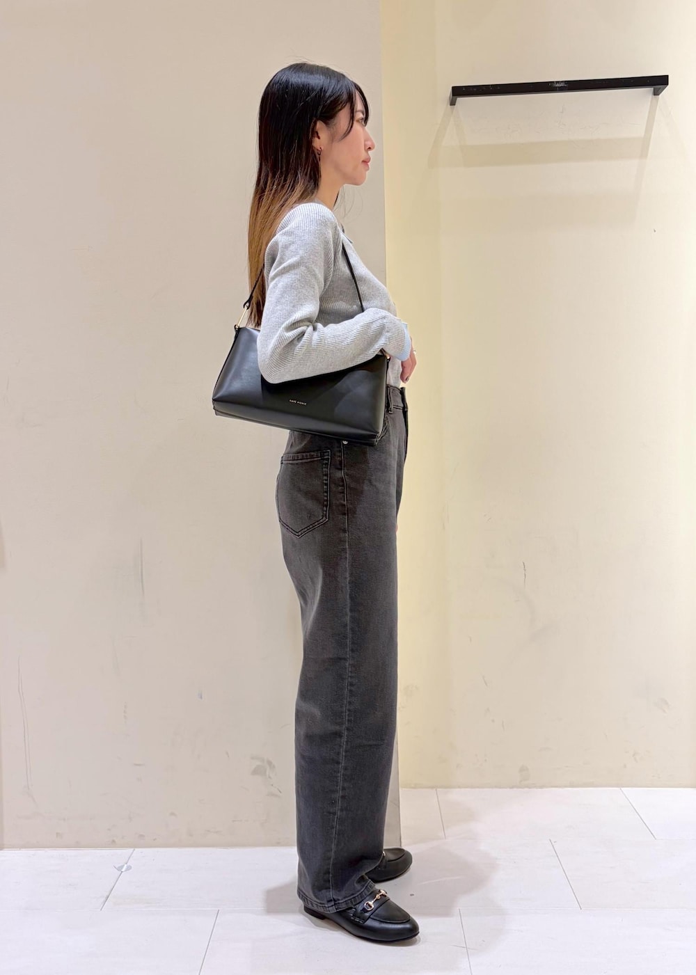 ブラック系のショルダーバッグ、ブラック系のローファー、グレー系のニット/セーターを着用したレディースの冬コーディネートの2枚目の写真