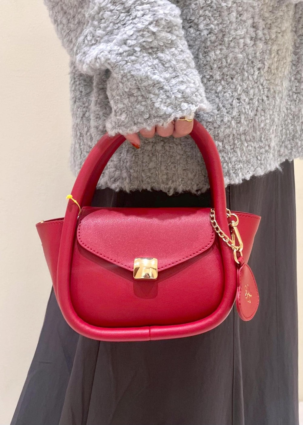 ホワイト系のニット/セーター、グレー系のスカート、レッド系のショルダーバッグを着用したレディースの冬コーディネートの9枚目の写真