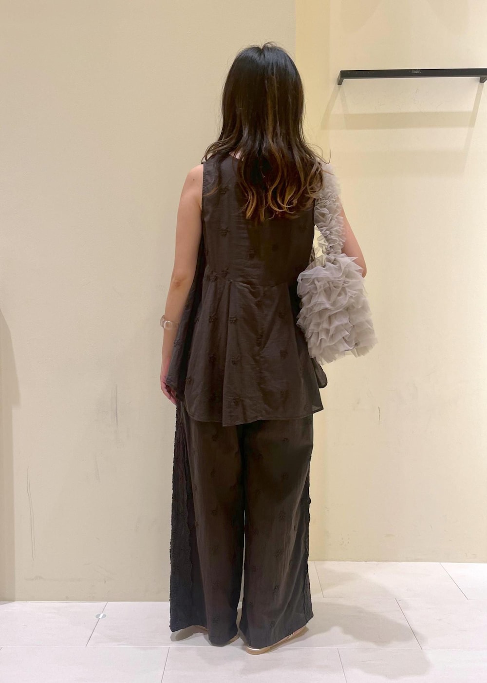 ベージュ系のショルダーバッグ、ゴールド系のサンダル、ブラック系のシャツ/ブラウスを着用したレディースの夏コーディネートの3枚目の写真