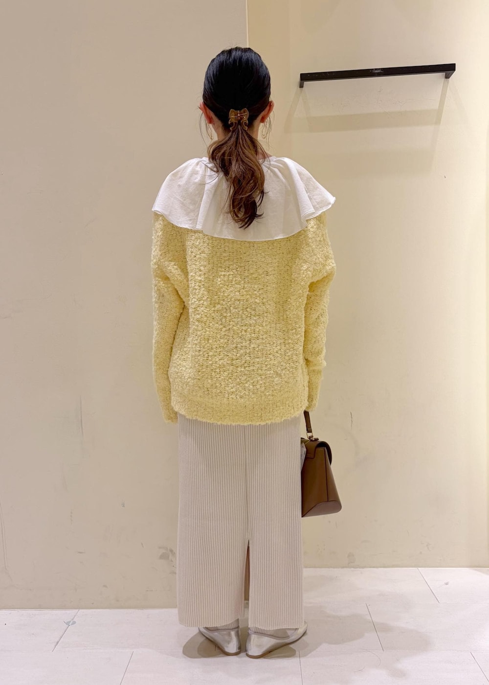 シルバー系のバレエシューズ、ホワイト系のシャツ/ブラウス、イエロー系のニット/セーターを着用したレディースの冬コーディネートの3枚目の写真