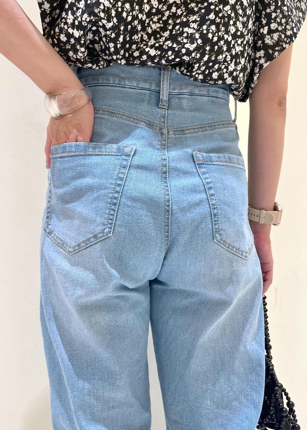 ブルー系のデニムパンツ、ブラック系のハンドバッグ、シルバー系のサンダルを着用したレディースの夏コーディネートの8枚目の写真