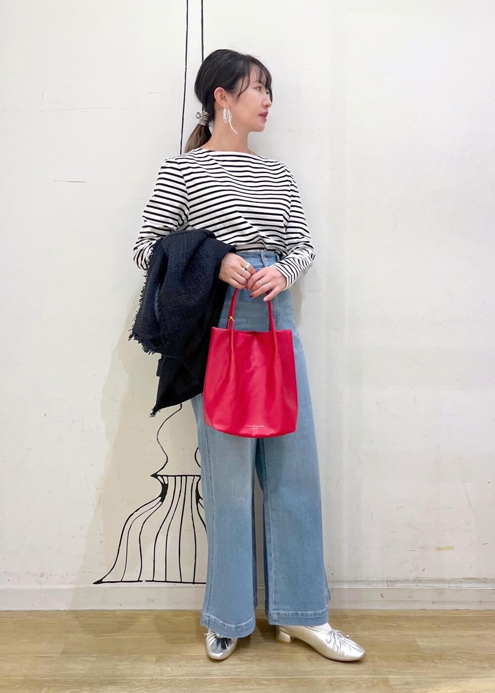 シルバー系のパンプス、ブルー系のデニムパンツ、レッド系のトートバッグを着用したレディースの冬コーディネートの5枚目の写真