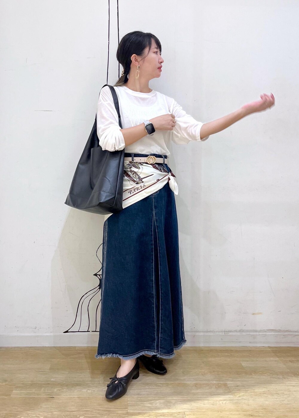 ブラック系のパンプス、ブラック系のトートバッグ、ブルー系のデニムスカートを着用したレディースの秋コーディネートの2枚目の写真