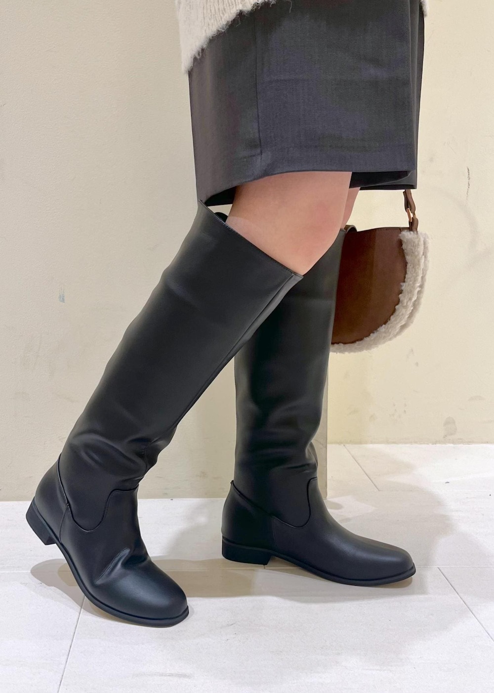 ブラック系のニット/セーター、ブラック系のブーツ、ブラウン系のショルダーバッグを着用したレディースの秋コーディネートの9枚目の写真