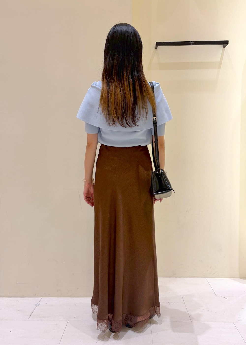 ブラック系のパンプス、ブルー系のニット/セーター、ブラウン系のスカートを着用したレディースの夏コーディネートの3枚目の写真