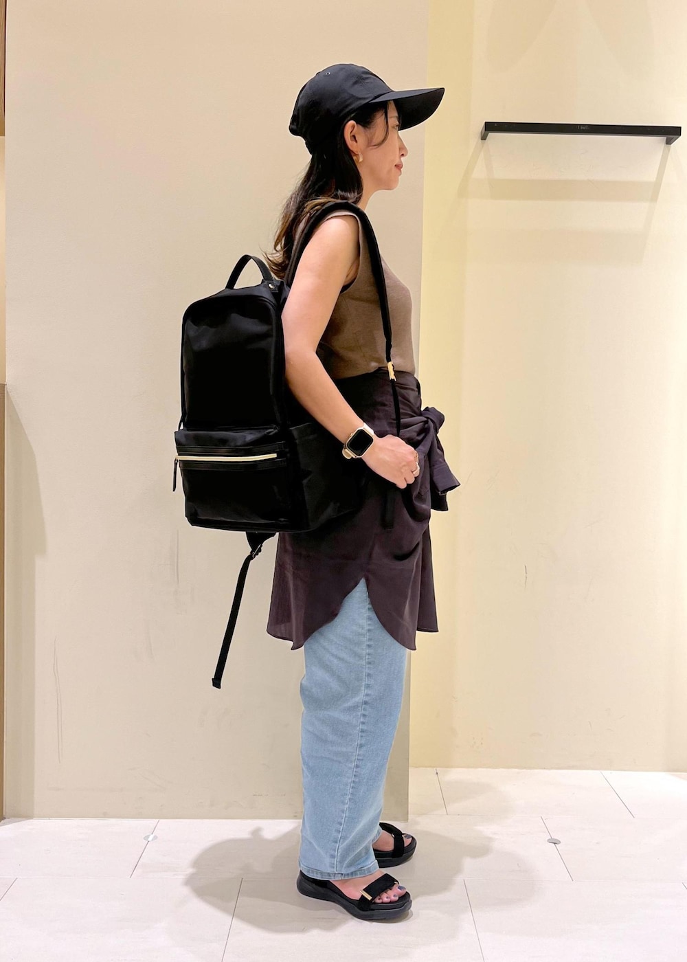 ブルー系のデニムパンツ、ブラック系のサンダル、ブラック系のバックパック/リュックを着用したレディースの夏コーディネートの2枚目の写真