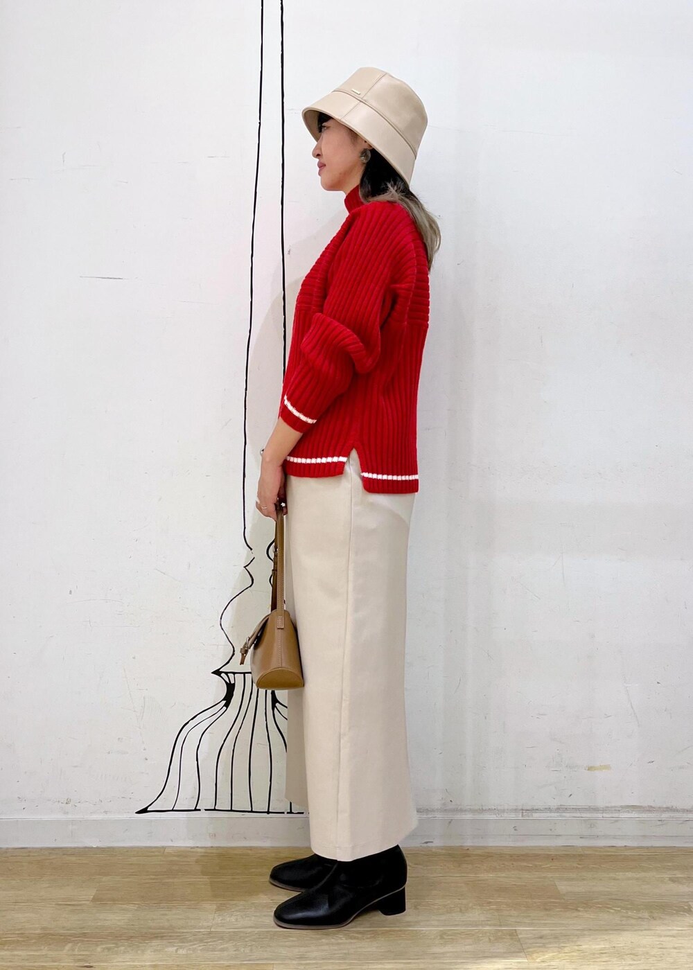 ベージュ系のスカート、レッド系のニット/セーター、ブラック系のブーツを着用したレディースの秋コーディネートの4枚目の写真