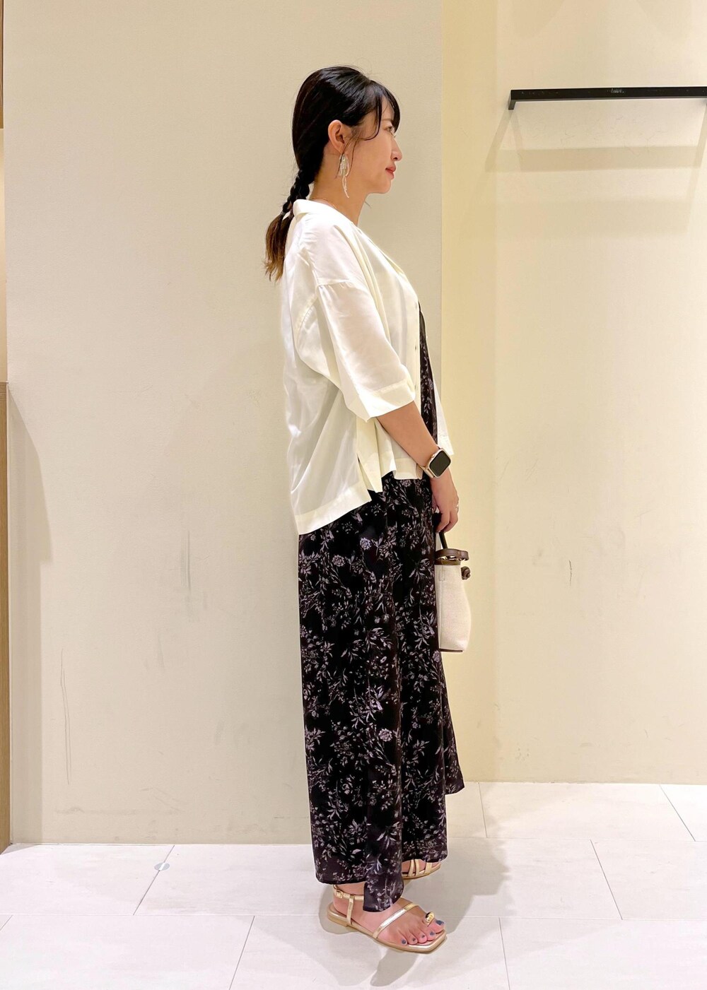 ブラウン系のトートバッグ、ゴールド系のサンダル、ブラック系のワンピースを着用したレディースの夏コーディネートの3枚目の写真