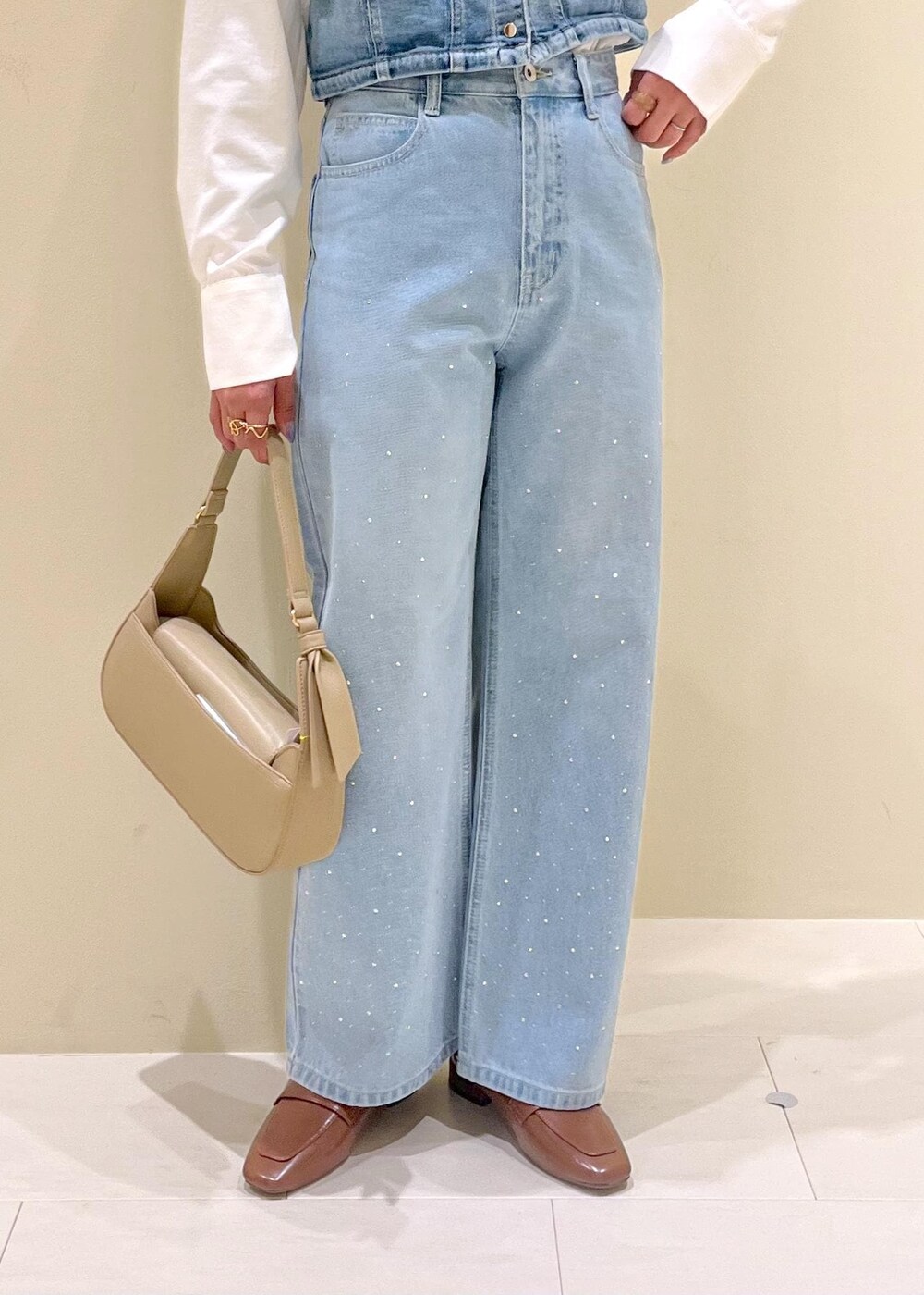 ベージュ系のハンドバッグ、ブルー系のデニムパンツ、ブルー系のベストを着用したレディースの春コーディネートの8枚目の写真