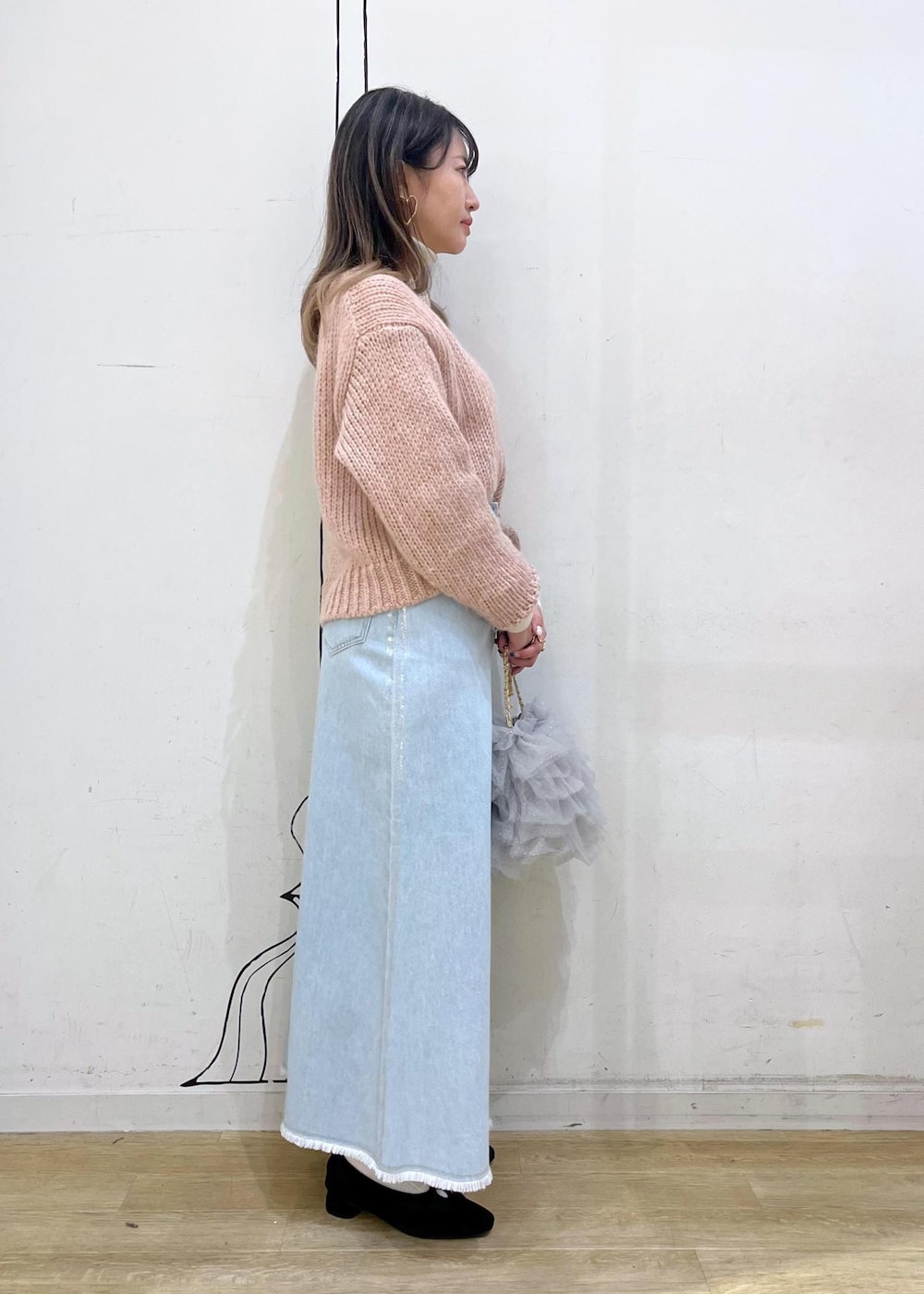 ホワイト系のニット/セーター、ブラック系のパンプス、ブルー系のデニムスカートを着用したレディースの冬コーディネートの4枚目の写真