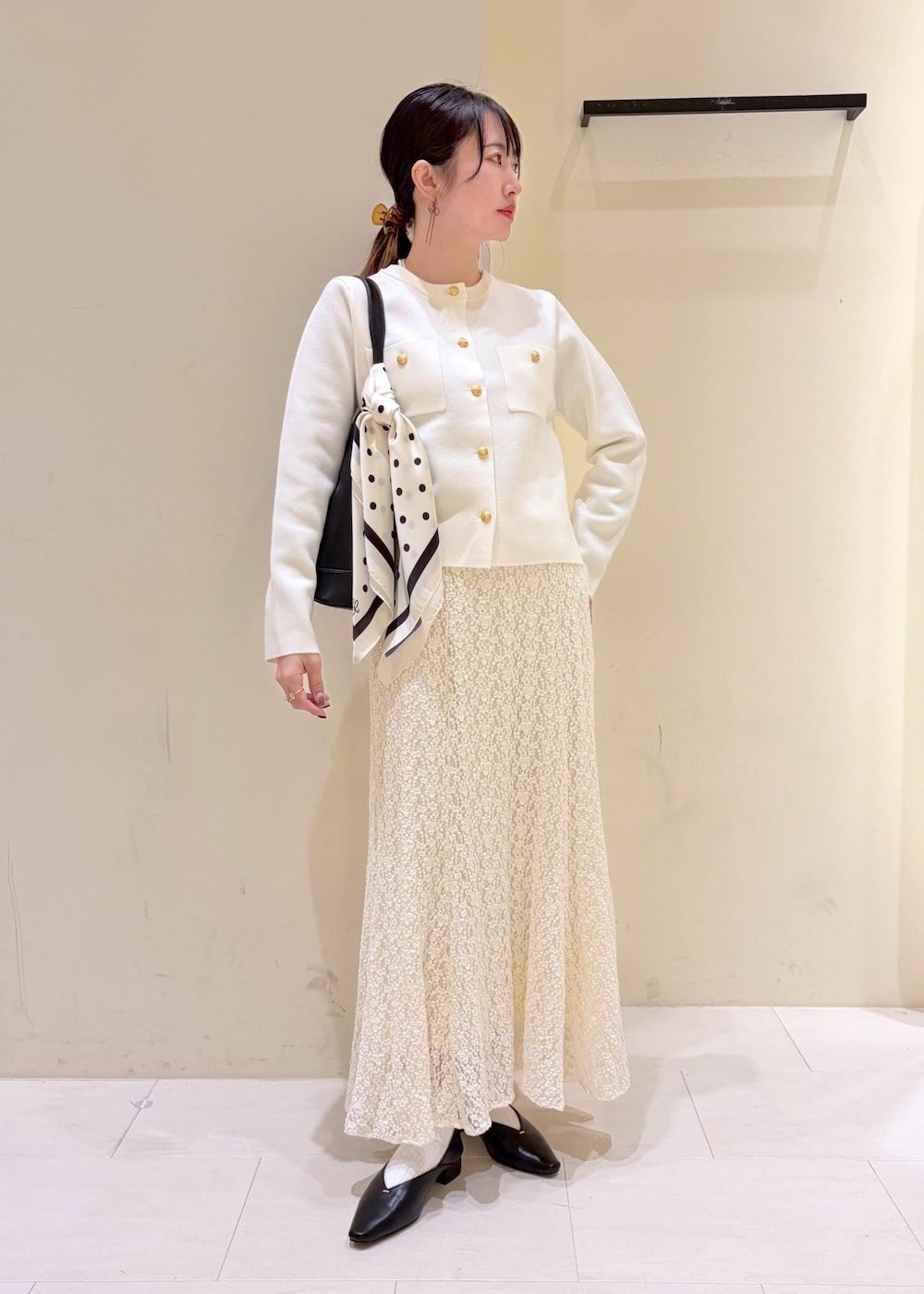 ブラック系のショルダーバッグ、ホワイト系のスカート、ホワイト系のカーディガン/ボレロを着用したレディースの冬コーディネートの10枚目の写真