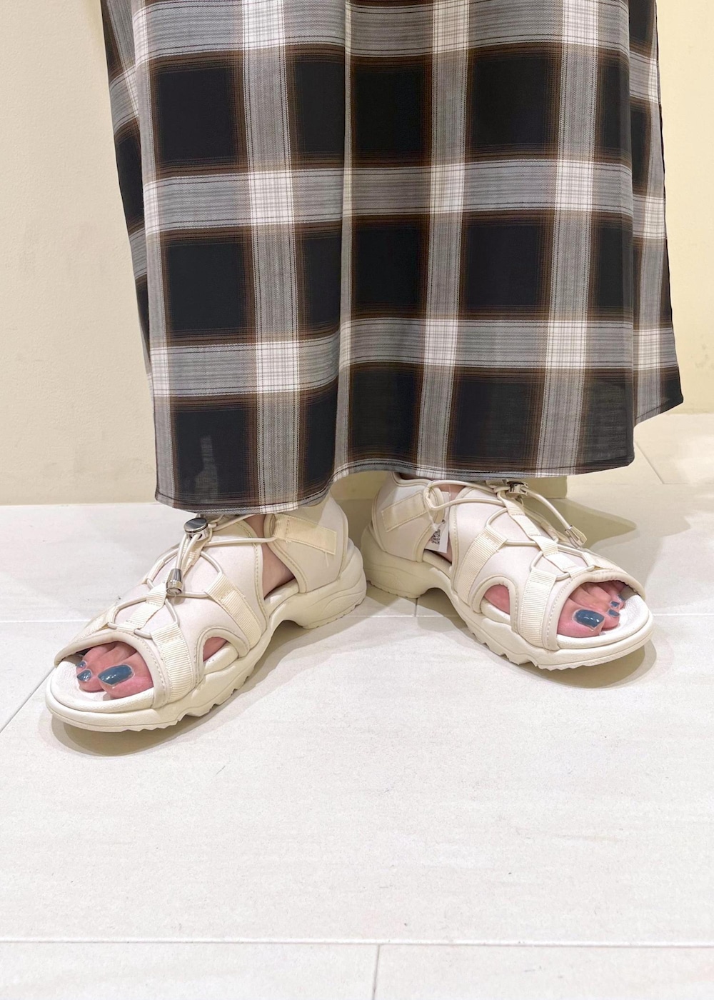 ホワイト系のトートバッグ、ホワイト系のサンダル、ブラック系のワンピースを着用したレディースの夏コーディネートの10枚目の写真