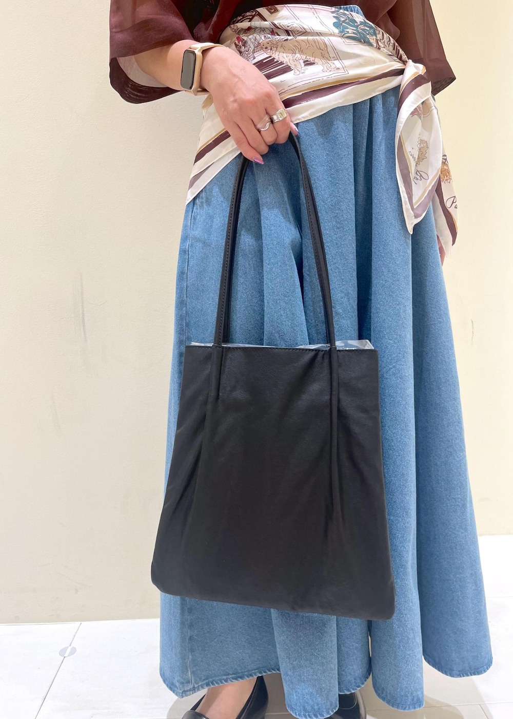 ブラック系のトートバッグ、ブラウン系のシャツ/ブラウス、ブルー系のスカートを着用したレディースの秋コーディネートの10枚目の写真