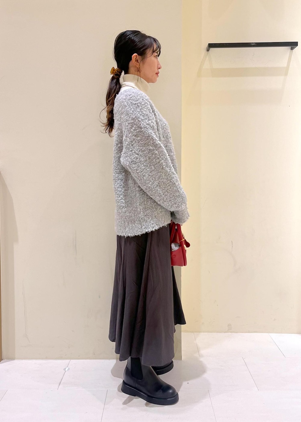 ホワイト系のニット/セーター、グレー系のスカート、レッド系のショルダーバッグを着用したレディースの冬コーディネートの3枚目の写真