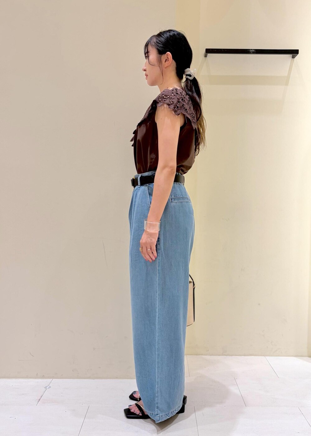 ブラック系のハンドバッグ、ブルー系のデニムパンツ、ブラック系のサンダルを着用したレディースの夏コーディネートの4枚目の写真