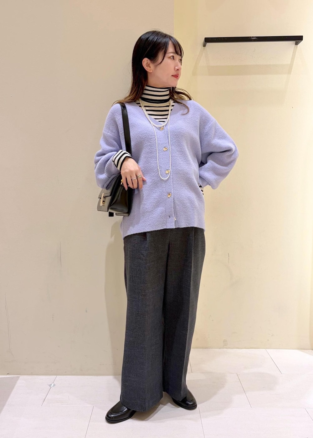 ブラック系のショルダーバッグ、ホワイト系のニット/セーター、グレー系のスラックスを着用したレディースの冬コーディネートの2枚目の写真