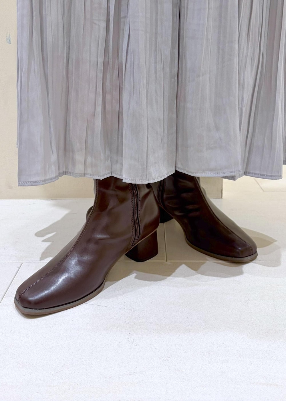 グレー系のスカート、ベージュ系のカーディガン/ボレロ、ホワイト系のトートバッグを着用したレディースの冬コーディネートの10枚目の写真