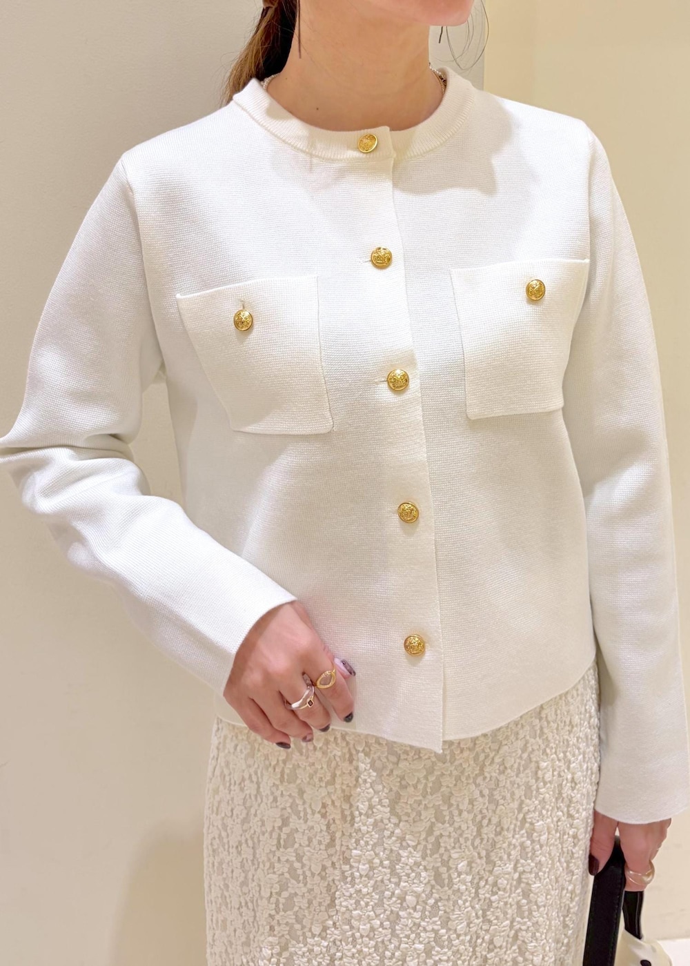 ブラック系のショルダーバッグ、ホワイト系のカーディガン/ボレロ、ホワイト系のスカートを着用したレディースの冬コーディネートの5枚目の写真