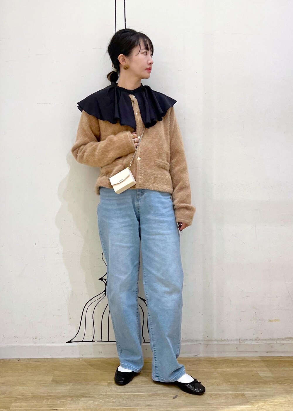 ブルー系のデニムパンツ、イエロー系のカーディガン/ボレロ、ホワイト系のショルダーバッグを着用したレディースの秋コーディネートの2枚目の写真