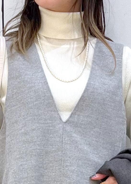 ホワイト系のショルダーバッグ、ブラック系のブーツ、ホワイト系のニット/セーターを着用したレディースの冬コーディネートの8枚目の写真