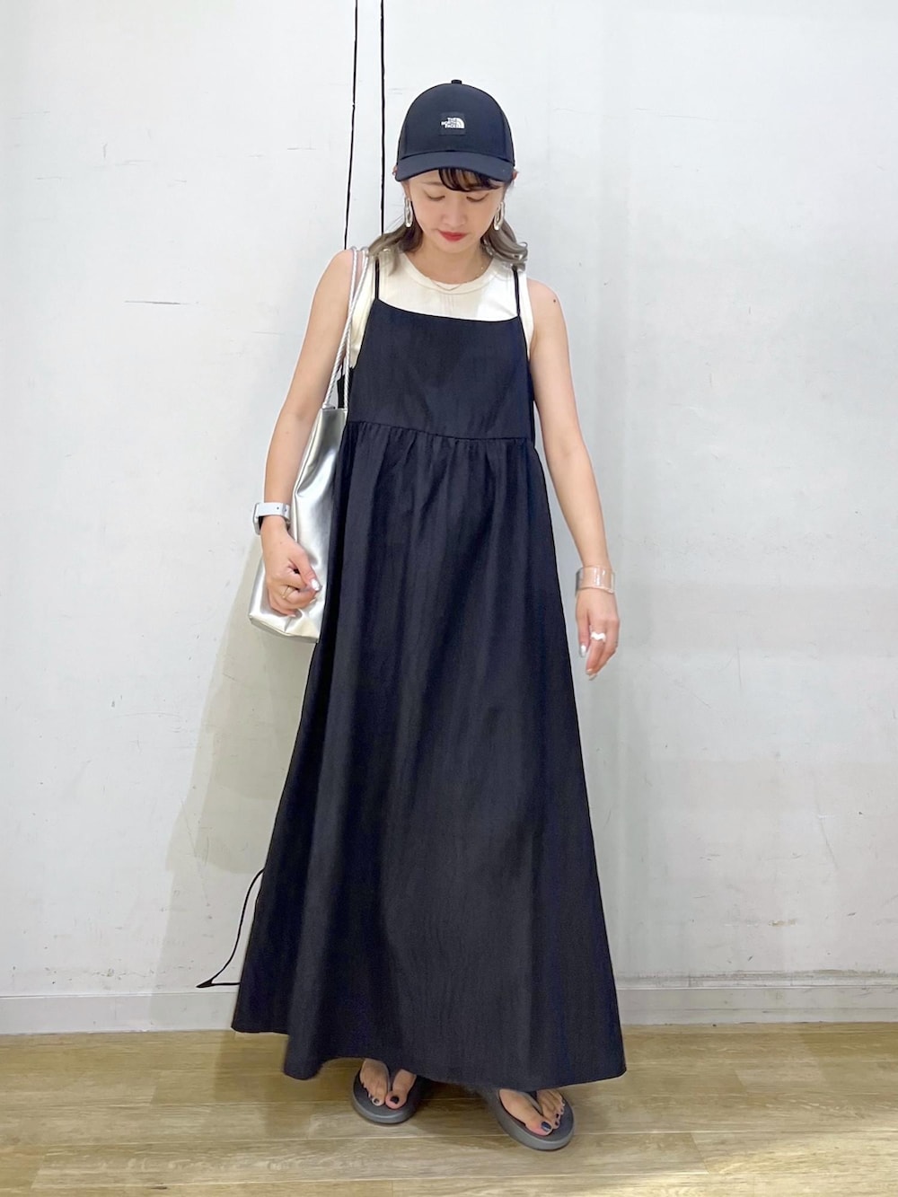 シルバー系のトートバッグ、ベージュ系のタンクトップ、ブラック系のワンピースを着用したレディースの夏コーディネートの2枚目の写真