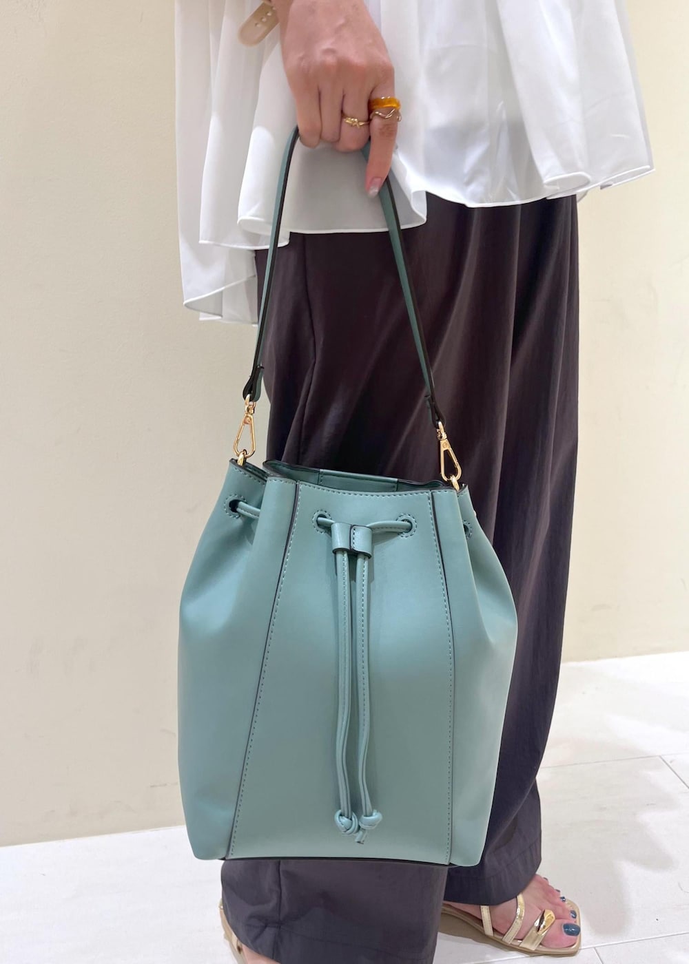 ブルー系のショルダーバッグ、グレー系のその他パンツ、ゴールド系のサンダルを着用したレディースの夏コーディネートの9枚目の写真