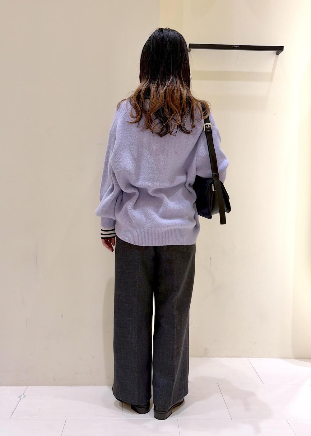 ブラック系のショルダーバッグ、ホワイト系のニット/セーター、グレー系のスラックスを着用したレディースの冬コーディネートの4枚目の写真