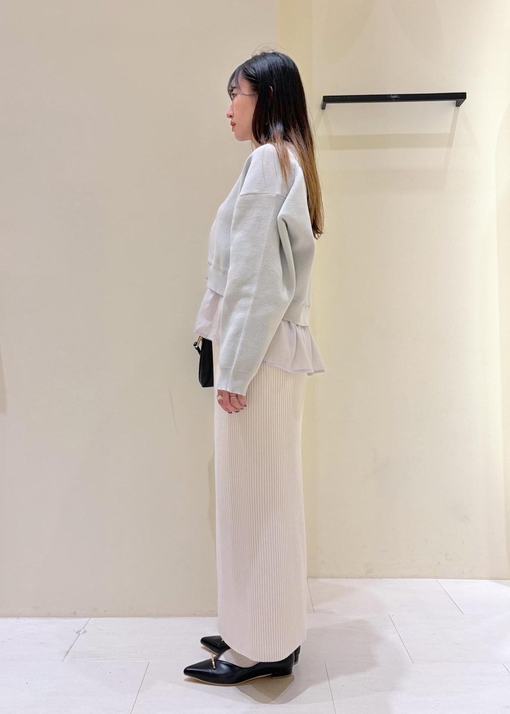 ブラック系のショルダーバッグ、ブラック系のパンプス、ホワイト系のスカートを着用したレディースの春コーディネートの2枚目の写真