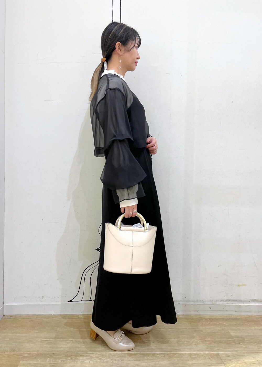 ベージュ系のローファー、ホワイト系のショルダーバッグ、ブラック系のドレスを着用したレディースの冬コーディネートの3枚目の写真