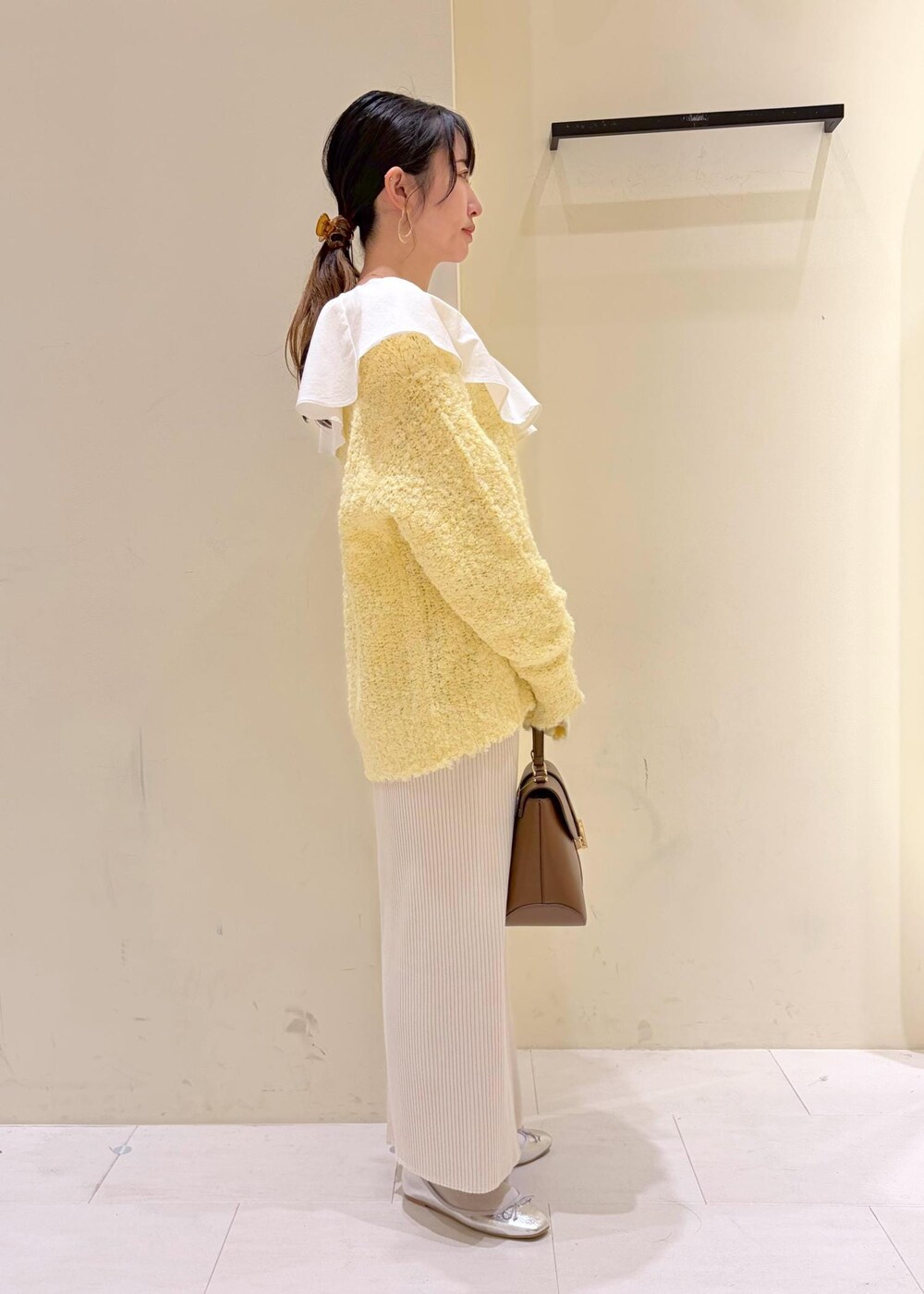 シルバー系のバレエシューズ、ホワイト系のシャツ/ブラウス、イエロー系のニット/セーターを着用したレディースの冬コーディネートの4枚目の写真