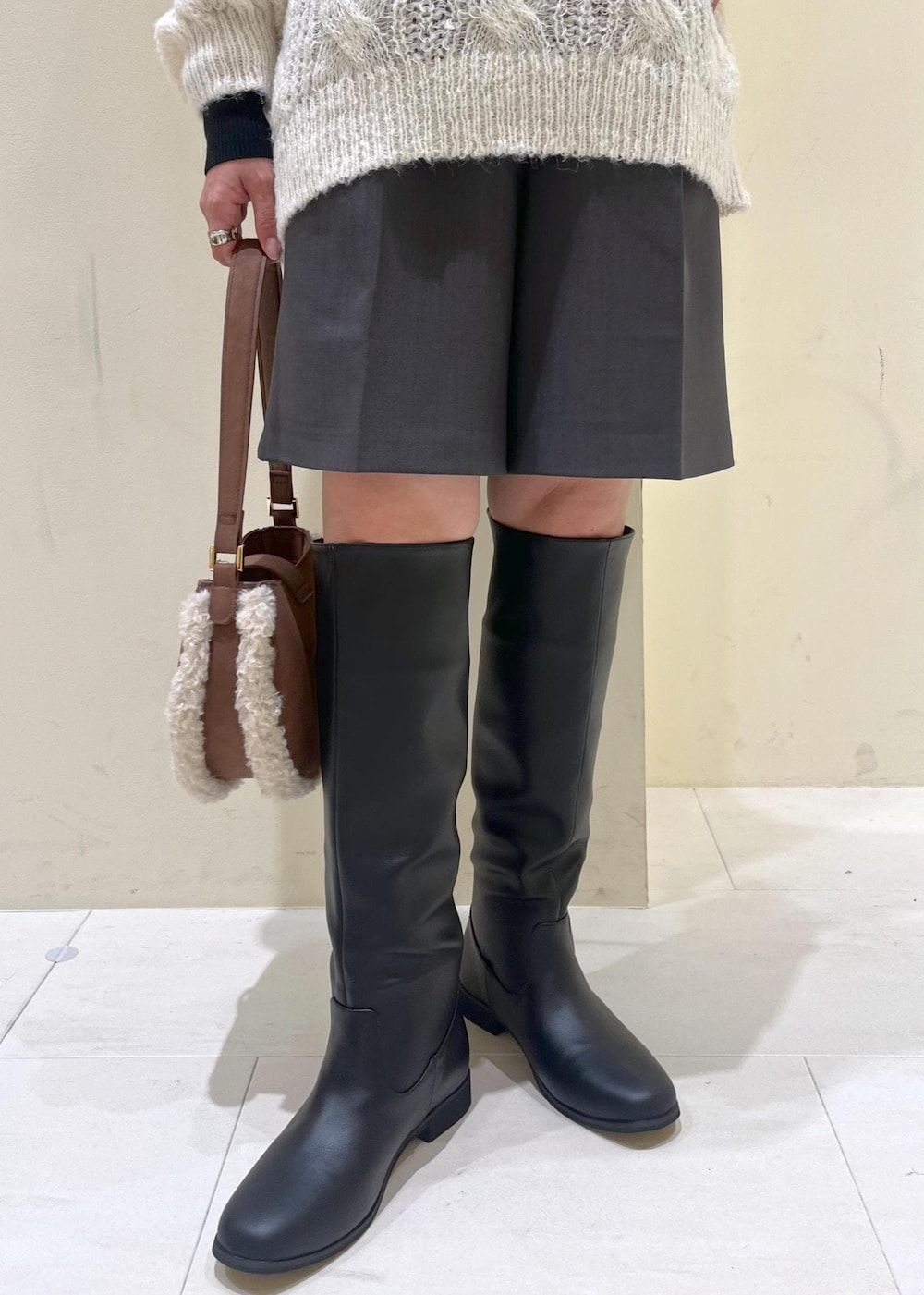 ブラック系のニット/セーター、ブラック系のブーツ、ブラウン系のショルダーバッグを着用したレディースの秋コーディネートの8枚目の写真