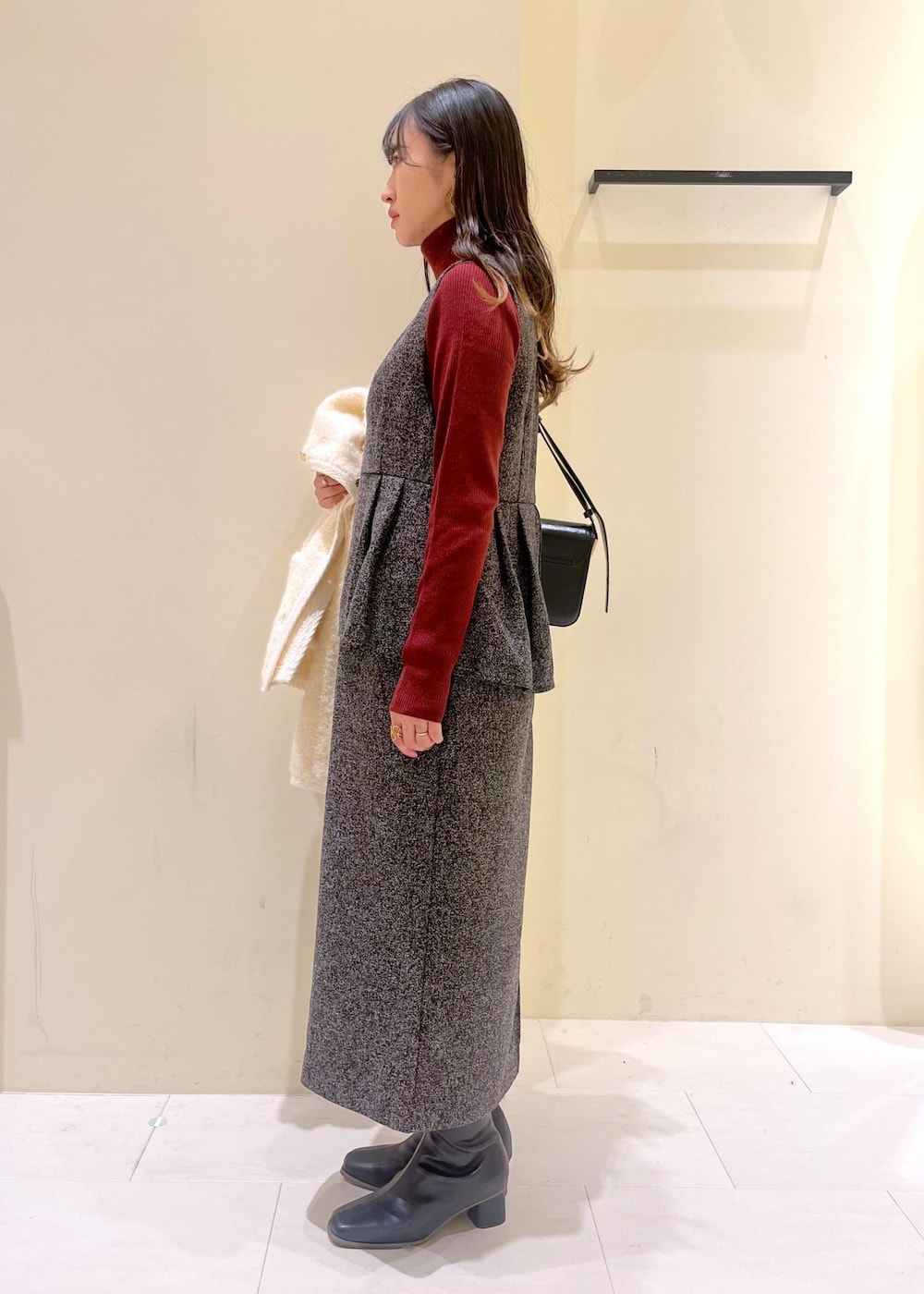 グレー系のジャンパースカート、ホワイト系のカーディガン/ボレロ、レッド系のニット/セーターを着用したレディースの冬コーディネートの2枚目の写真