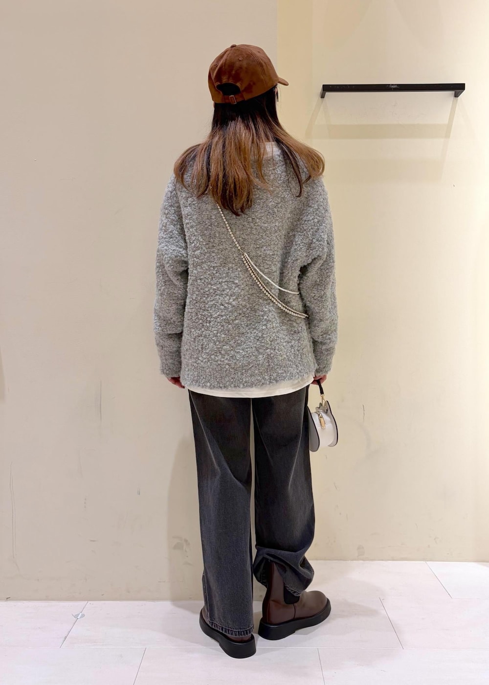 ブラック系のデニムパンツ、ブラウン系のブーツ、グレー系のニット/セーターを着用したレディースの冬コーディネートの3枚目の写真