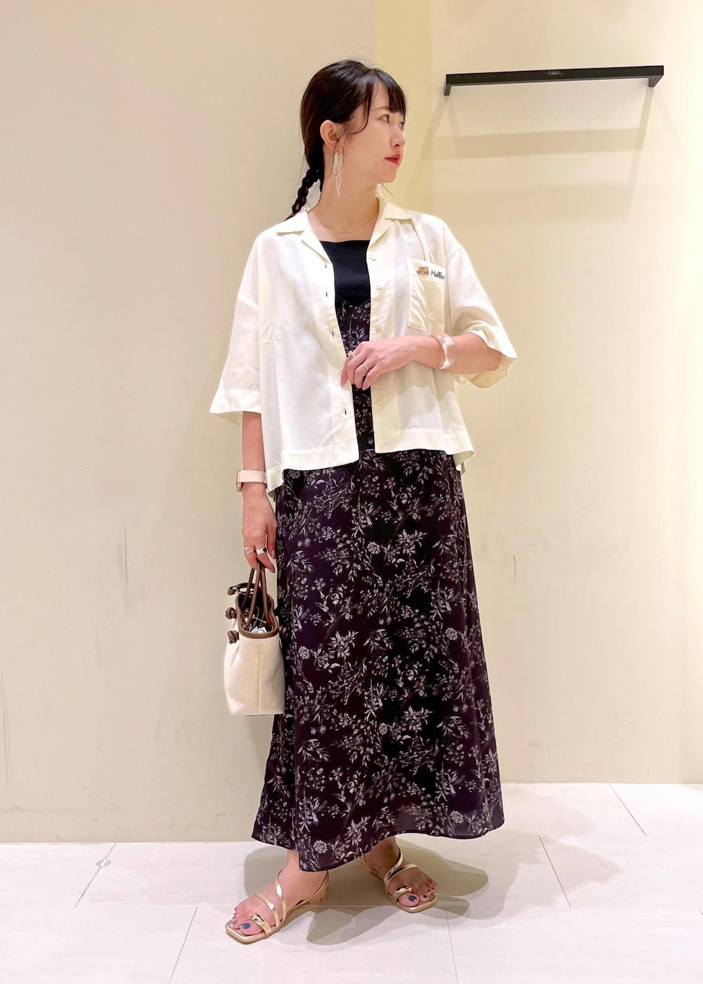 ブラウン系のトートバッグ、ゴールド系のサンダル、ブラック系のワンピースを着用したレディースの夏コーディネートの2枚目の写真