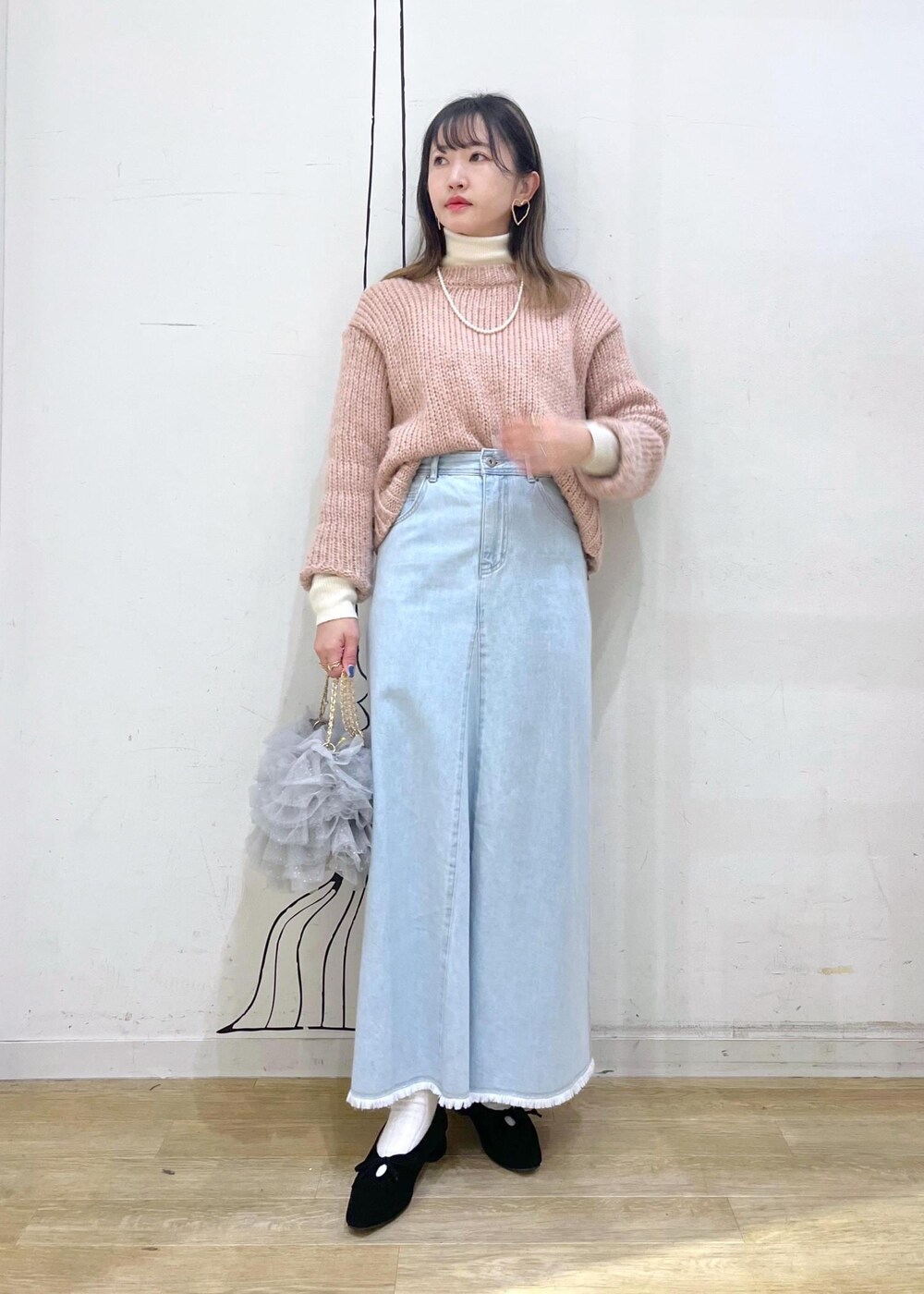 ホワイト系のニット/セーター、ブラック系のパンプス、ブルー系のデニムスカートを着用したレディースの冬コーディネートの2枚目の写真