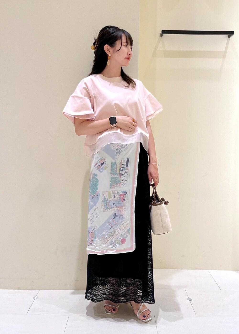 シルバー系のサンダル、ブラウン系のトートバッグ、ブラック系のスカートを着用したレディースの夏コーディネートの2枚目の写真