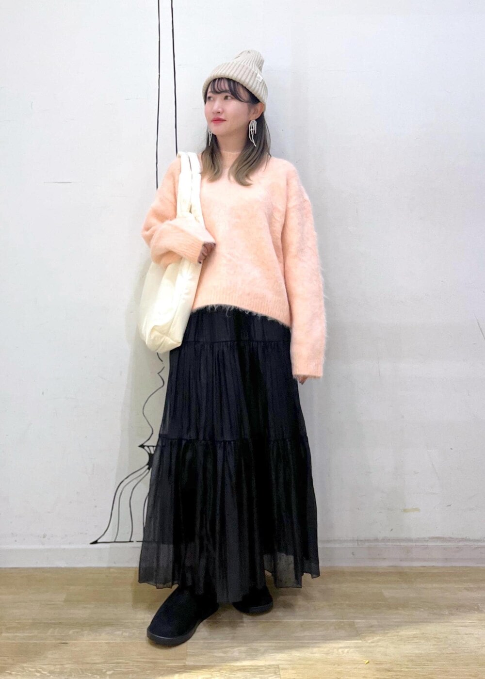 ホワイト系のトートバッグ、ピンク系のニット/セーター、ブラック系のスカートを着用したレディースの冬コーディネートの3枚目の写真