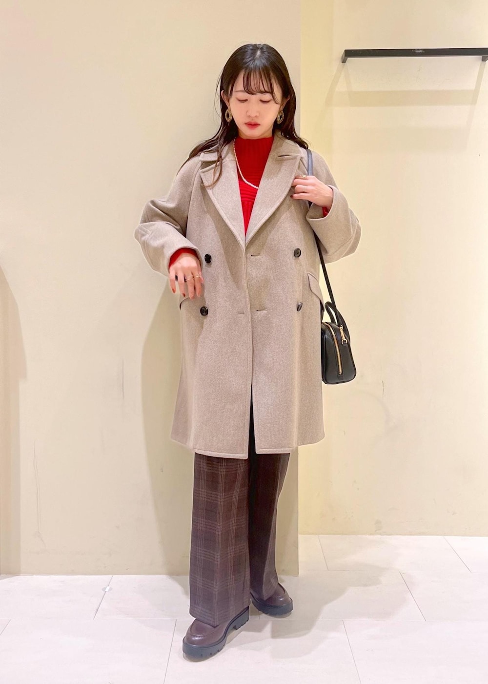 ブラック系のショルダーバッグ、レッド系のニット/セーター、ブラウン系のピーコートを着用したレディースの冬コーディネートの10枚目の写真