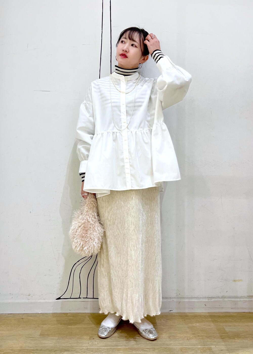 ベージュ系のハンドバッグ、ホワイト系のニット/セーター、シルバー系のバレエシューズを着用したレディースの冬コーディネートの3枚目の写真