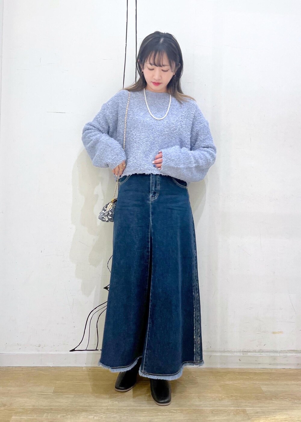 ブラック系のブーツ、グレー系のショルダーバッグ、ブルー系のデニムスカートを着用したレディースの冬コーディネートの2枚目の写真