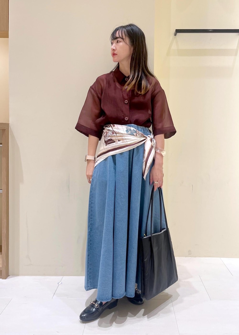 ブラック系のトートバッグ、ブラウン系のシャツ/ブラウス、ブルー系のスカートを着用したレディースの秋コーディネートの2枚目の写真