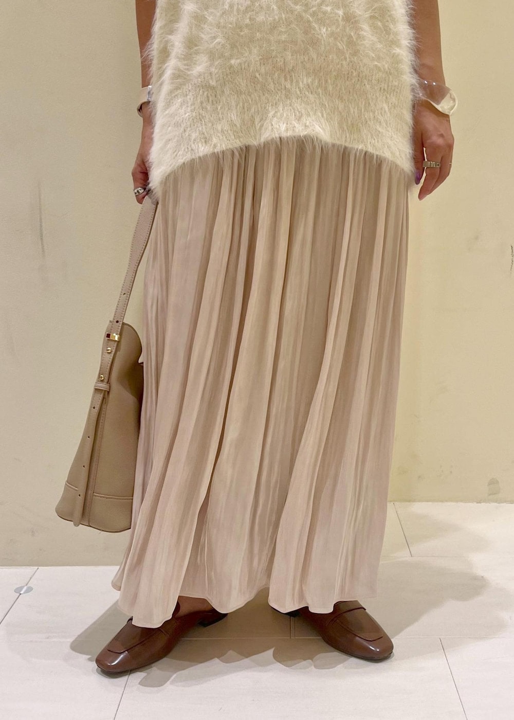 イエロー系のローファー、ベージュ系のスカート、ベージュ系のショルダーバッグを着用したレディースの夏コーディネートの8枚目の写真