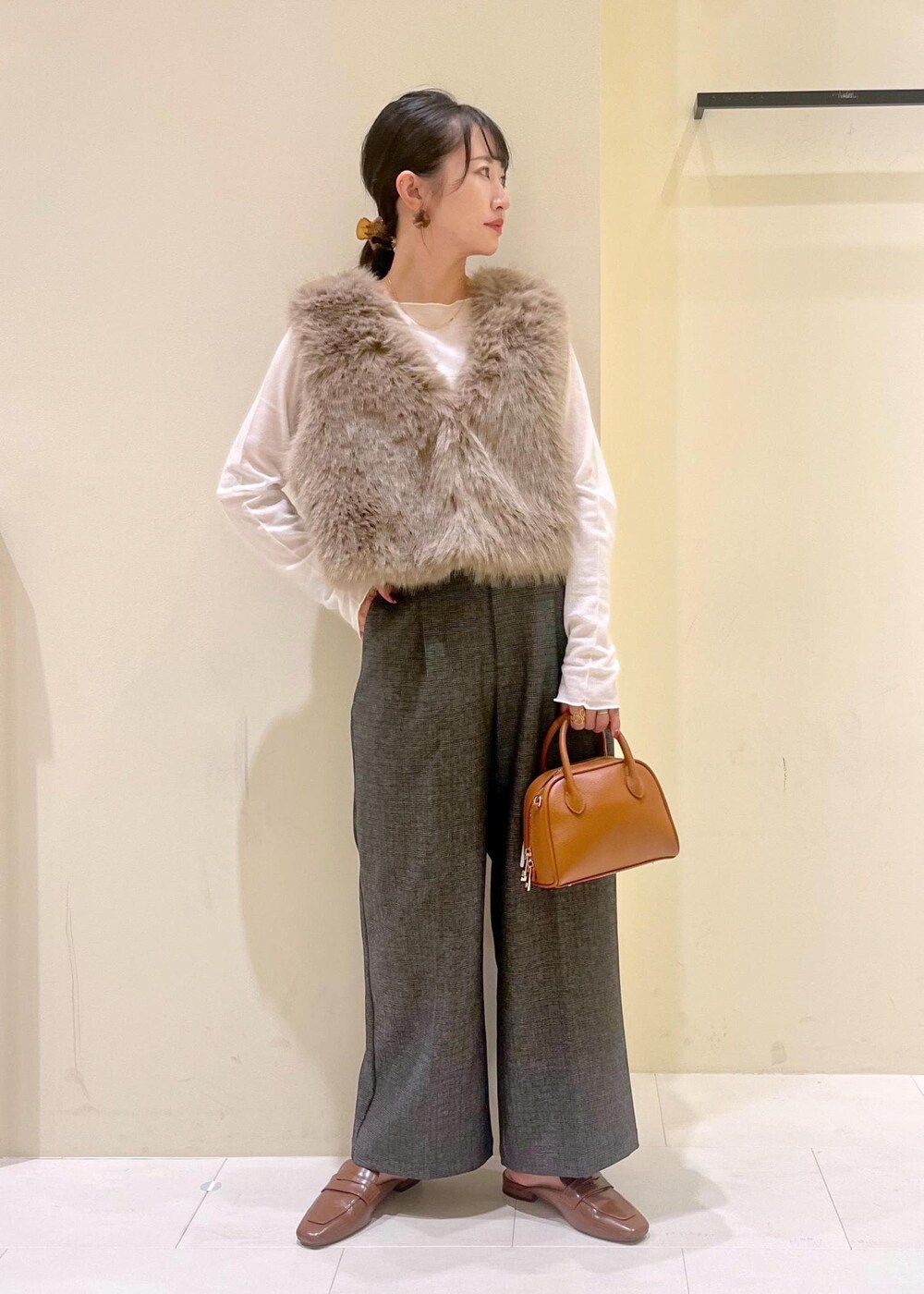 ブラウン系のベスト、ホワイト系のTシャツ/カットソー、グレー系のスラックスを着用したレディースの秋コーディネートの2枚目の写真