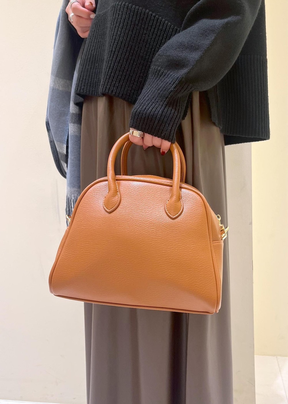 ブラウン系のスカート、ブラウン系のボストンバッグ、ブラック系のニット/セーターを着用したレディースの秋コーディネートの9枚目の写真