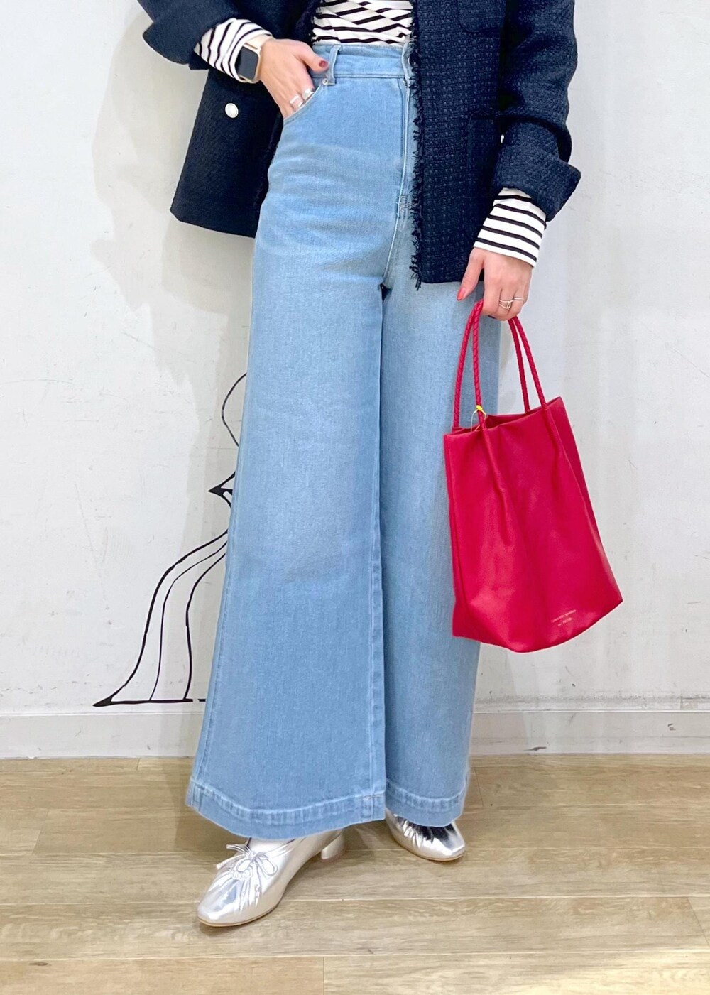 シルバー系のパンプス、ブルー系のデニムパンツ、レッド系のトートバッグを着用したレディースの冬コーディネートの7枚目の写真