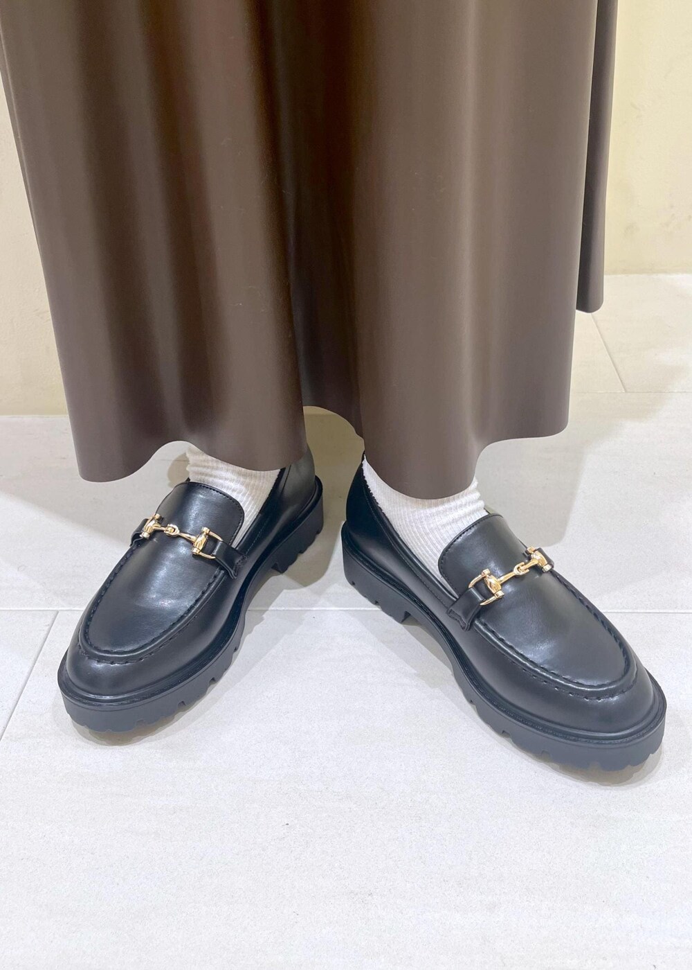 ブラウン系のスカート、ブラウン系のボストンバッグ、ブラック系のニット/セーターを着用したレディースの秋コーディネートの10枚目の写真