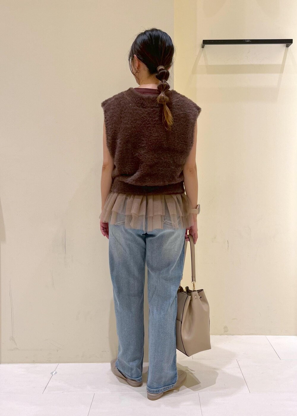 グレー系のローファー、ブルー系のデニムパンツ、ベージュ系のショルダーバッグを着用したレディースの夏コーディネートの4枚目の写真