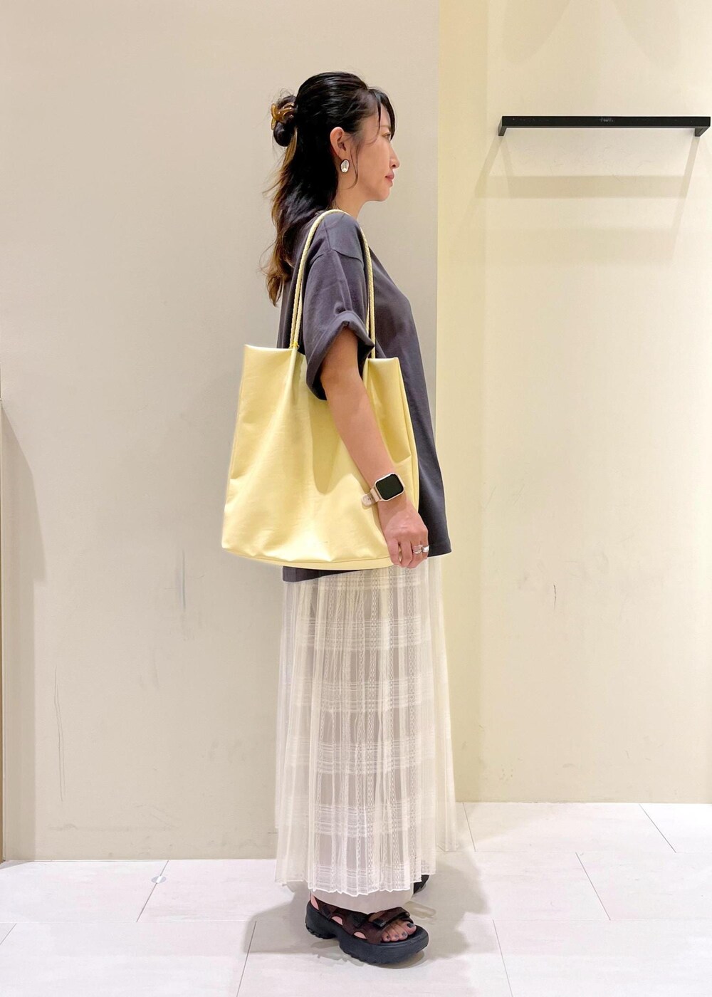 イエロー系のトートバッグ、ホワイト系のスカート、ベージュ系のその他パンツを着用したレディースの夏コーディネートの3枚目の写真